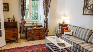A cozy living room with a vintage trunk, a striped sofa, and a small table with decorative items. - A Happy stay by Edem Beach (Palaio Faliro)
