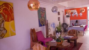 A modern hotel lobby with a wooden reception desk, a seating area with a pink chair, and artwork on the walls. - Nne-Era Residence (Lagos)