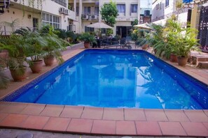 A rectangular pool with clear blue water, surrounded by potted plants and outdoor furniture. - Nne-Era Residence (Lagos)