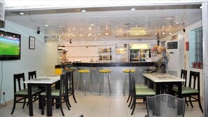 A restaurant with a bar area, multiple tables and stools, and a television mounted on the wall. - Nne-Era Residence (Lagos)