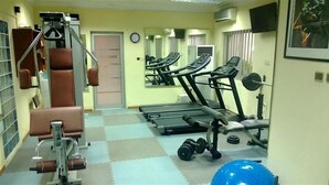 A gym with exercise equipment, a mirror, and a door labeled "EXIT". - Nne-Era Residence (Lagos)