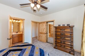 A bedroom with a bed, a dresser, a ceiling fan, and a mirror.