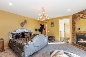 Un dormitorio con cama, candelabro, chimenea y monturas de animales en la pared.