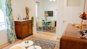 Een ruimtelijk ingerichte leefruimte met een eethoek, een houten kast en een kleine tafel met decoratieve objecten.