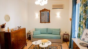 Een woonkamer met een bank, een houten kast, een spiegel en een kamerkleed met dessin.