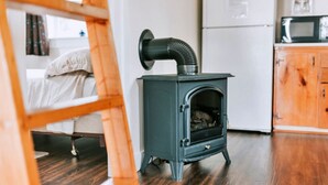 A compact kitchen with a wood-burning stove, a refrigerator, and a microwave. - Anchorage House & Cottages - Bayswater Cottage (Hubbards)