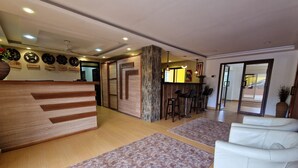 A reception area with a wooden reception desk, a bar with stools, and a white sofa.
