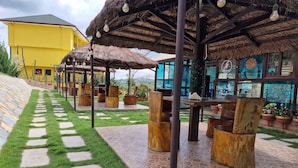 A courtyard with thatched-roof structures, outdoor seating, and a pathway.