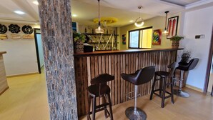 A modern bar area with wooden accents, a high ceiling, and a view of the city.