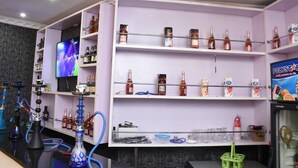 Una zona de bar con estantes llenos de botellas, un televisor y un refrigerador Polystar.