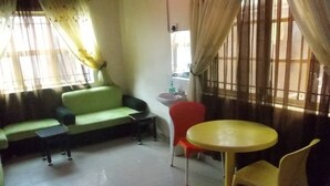 Una habitación con un sofá verde, una mesa pequeña, una mesa amarilla y una silla roja.