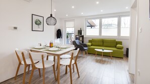 Ett modernt vardagsrum med en matplats, en grön soffa och ett litet bord.