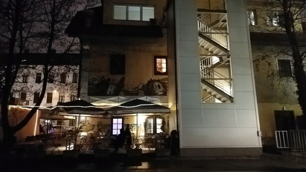 En byggnad med flera våningar, en central trappa, ett utomhusområde med sittplatser och ett café.