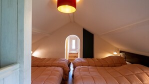 Ein Schlafzimmer mit zwei Betten, einer roten Lampe und einem Dachfenster.