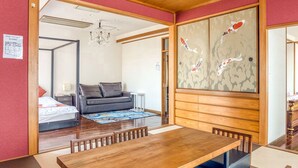 A traditional Japanese-style room with tatami flooring, a low wooden table, a sofa, and a sliding door with a decorative fish pattern. - Woo House (Osaka)