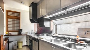 A modern kitchen with stainless steel appliances, a black range hood, and a large window with a view. - Woo House (Osaka)