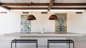 Ein modernes Interieur mit zwei schwarzen Metallbänken, einem weißen Podest und zwei hängenden Pendelleuchten.