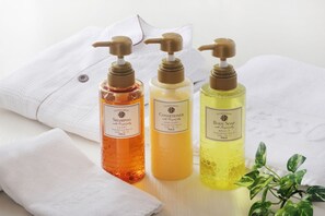 Three bottles of shower products on a white towel. - Keio Presso Inn Kanda (Tokyo)
