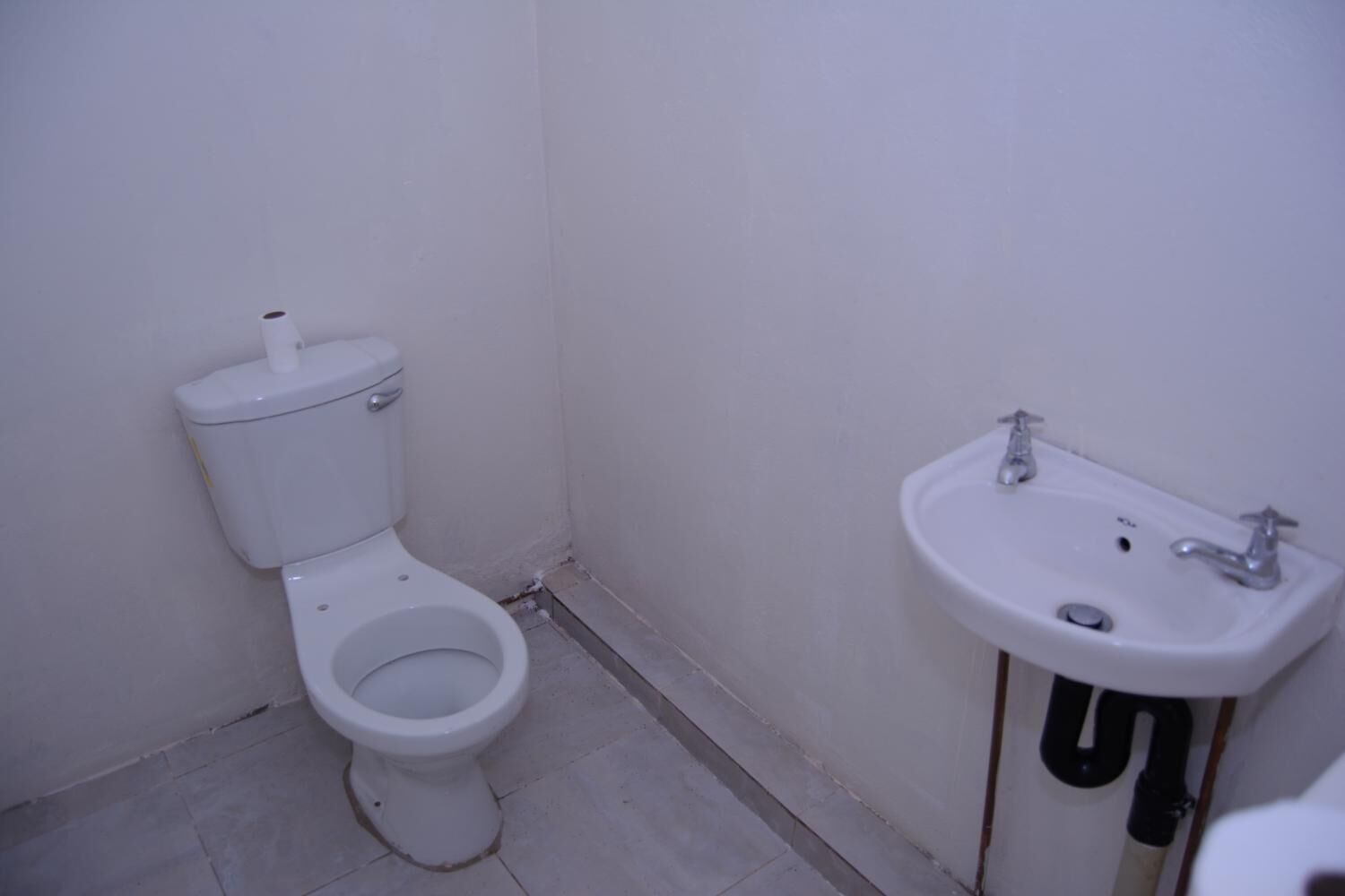 A small, basic bathroom with a toilet and a sink.