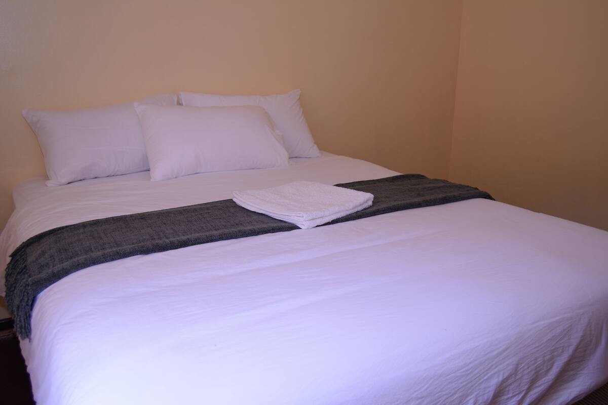 A neatly made bed with white linens and a folded white towel.