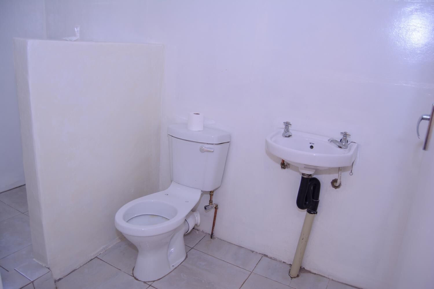 Ein kleines, weißes Badezimmer mit Toilette und Waschbecken.