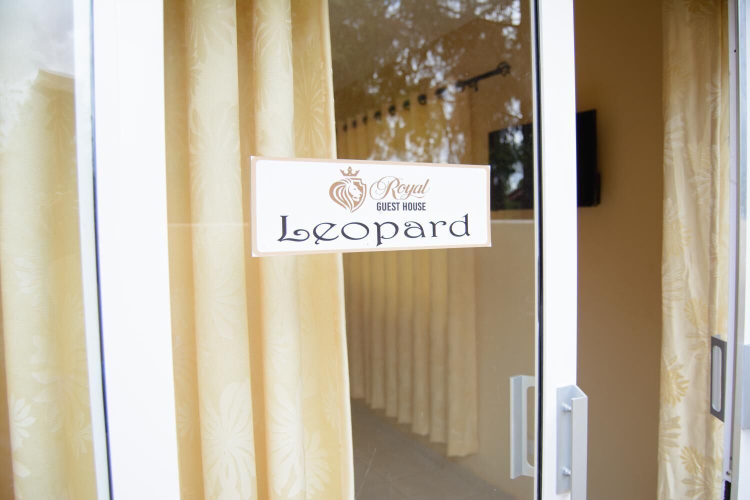 A sign for the Royal Guest House Leopard, indicating the entrance to a building with a patterned curtain.