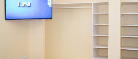 A room with a television displaying the logo "DSI" on the wall, a built-in shelving unit, and a wooden floor.