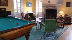 A cozy room with a pool table, comfortable seating, a fireplace, and artwork on the walls. - Chateau De Clusors (Saint-Menoux)