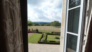 A view from a window with a view of a well-maintained garden and a distant landscape. - Chateau De Clusors (Saint-Menoux)