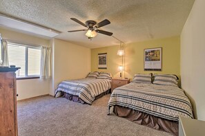 A bedroom with two beds, a ceiling fan, a window with blinds, and a lamp on the nightstand. - Angel Fire Mtn Escape: Walk to Chile Express Lift! (Angel Fire)