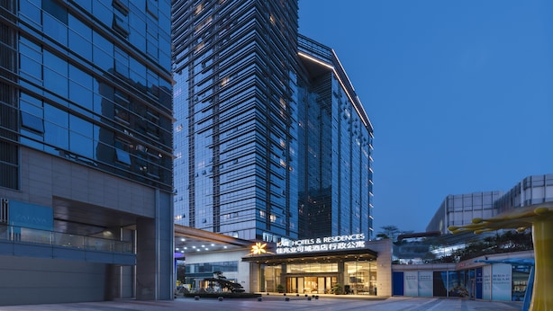 A modern hotel with a prominent glass facade, a well-lit entrance, and a clear view of the surrounding urban environment. - Kare Hotels (Shenzhen)
