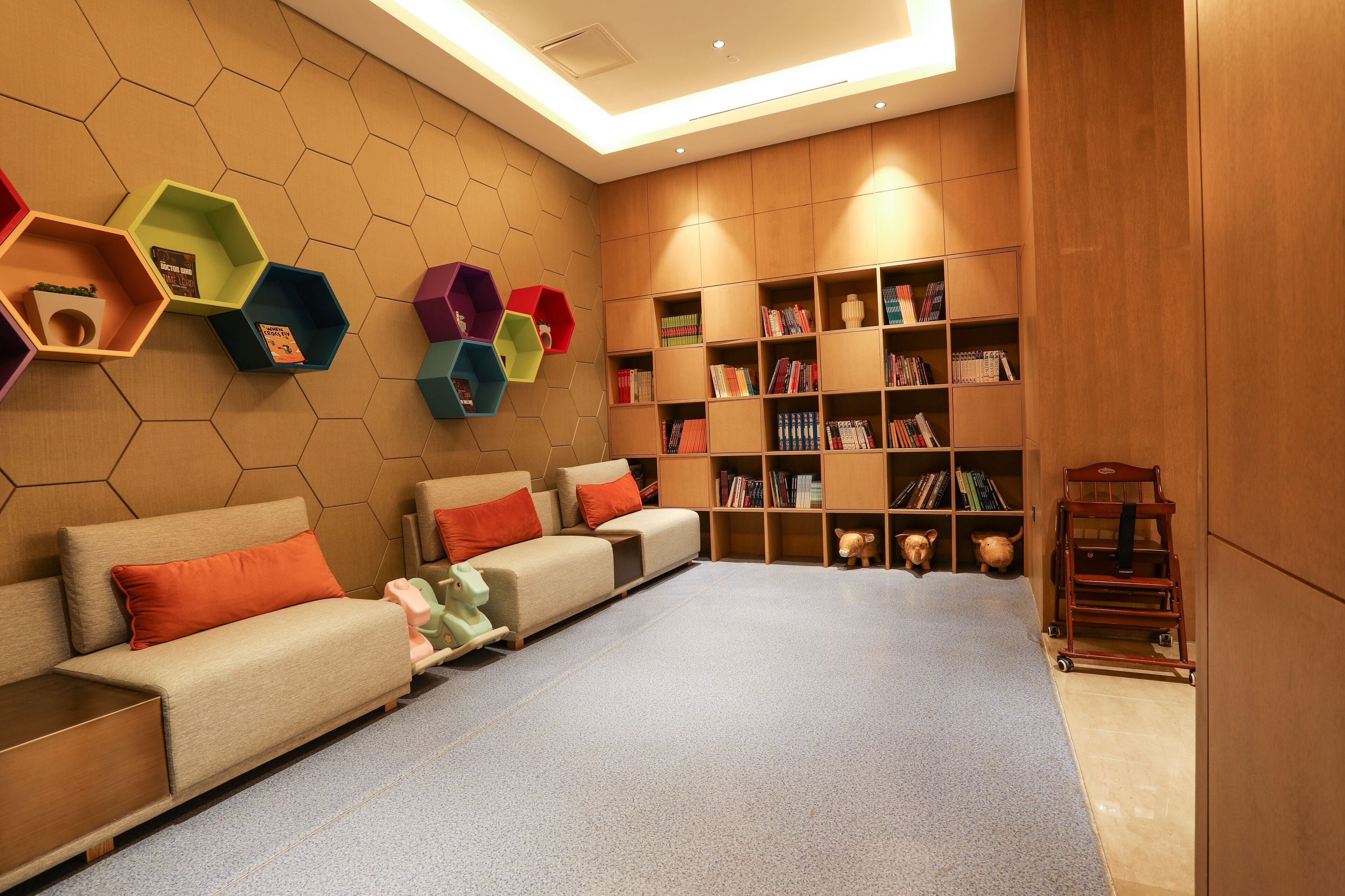 A modern library with a sofa, hexagonal shelves, and a wooden bookshelf.
