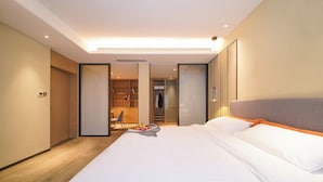 A modern hotel room with a large bed, a wardrobe, a seating area, and a view into the hallway. - Kare Hotels (Shenzhen)