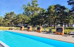 A swimming pool with lounge chairs and a view of trees.