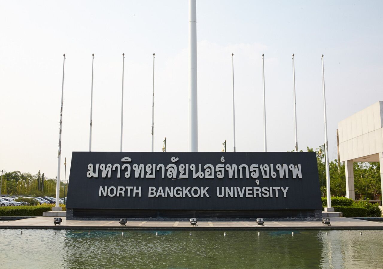 Une enseigne indiquant l’emplacement de l’université du nord de Bangkok, avec une piscine devant.