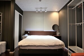 A modern hotel room with a large bed, a bedside table, a wardrobe, and a ceiling light fixture. - Tamade Sakura House (Osaka)
