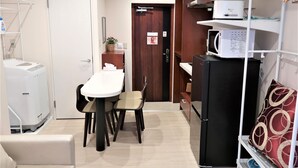 Una cocina compacta con una mesa de comedor, sillas, un refrigerador y un microondas.