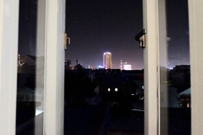 Una vista nocturna de la ciudad a través de una ventana, con edificios iluminados.