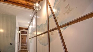 A hallway with wooden beams, a hanging light fixture, and a wall with abstract designs. - DELUX APARTMENT CASA DEL ANILLO TOLEDO (Toledo)
