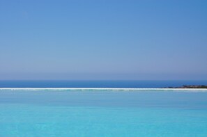 Ein freier Blick auf einen Strand mit türkisblauem Wasser und einer fernen Küstenlinie.