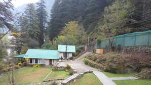 A house with a green roof, a stone pathway, and a garden. - Asaka Himalayan Inspiration lodge Kasol (Bhuntar)