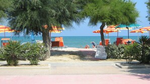 A beachside area with multiple beach umbrellas, lounge chairs, and a clear view of the sea. - Victoria Mobilehome Village Residence Juliamare (Giulianova)