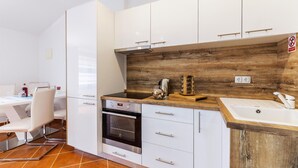 A modern kitchen with white cabinets, a wooden backsplash, and a built-in oven. - 1 bedroom nice apartment in Pavicini (Pavicini)