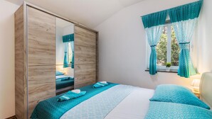A bedroom with a bed, a wardrobe, a window with curtains, and a bedside lamp. - 1 bedroom nice apartment in Pavicini (Pavicini)