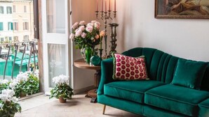Ein grünes Sofa mit einem polkadot-Kissen, eine Vase mit rosafarbenen Blumen und ein Kandelaber mit brennenden Kerzen.