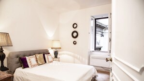 Ein Schlafzimmer mit Bett, Nachttischlampen, einem Fenster und einer Tür.