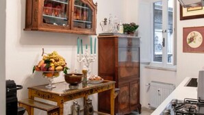 Eine Küche mit einem Holzschrank, einem Glastisch mit Obst, einer Kandelaber und einem Herd.