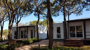 A modern building with a white facade, large windows, and a paved entrance area with a bench. - Victoria Mobilehome Tortoreto Lido (Tortoreto)