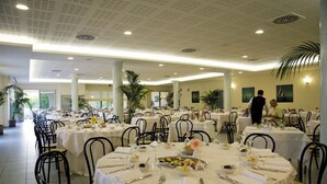 A spacious banquet hall with multiple round tables set for dining, featuring white tablecloths and black chairs. - Victoria Mobilehome Tortoreto Lido (Tortoreto)