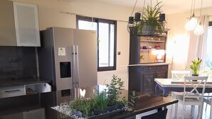 Ett modernt kök med en svart bänkskiva, rostfria vitvaror och en matplats med bord och stolar.